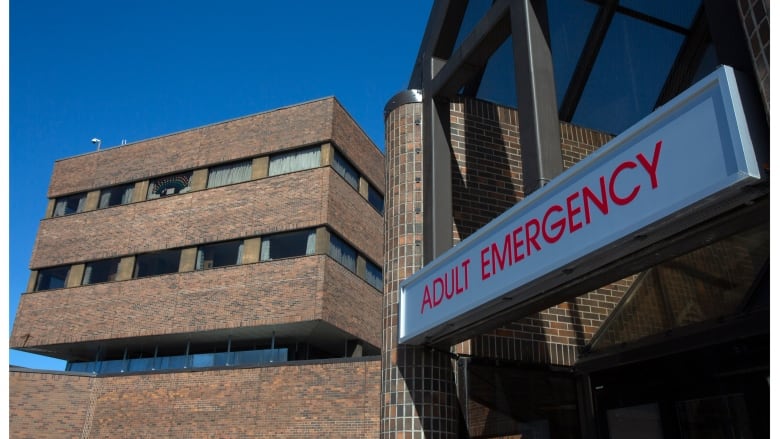 A hospital sign reading Adult Emergency, above the entrance to a hospital.