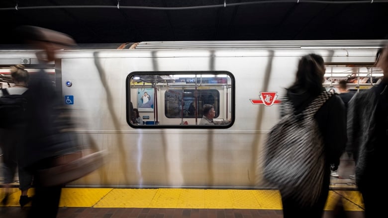 a subway train underground rushes by people