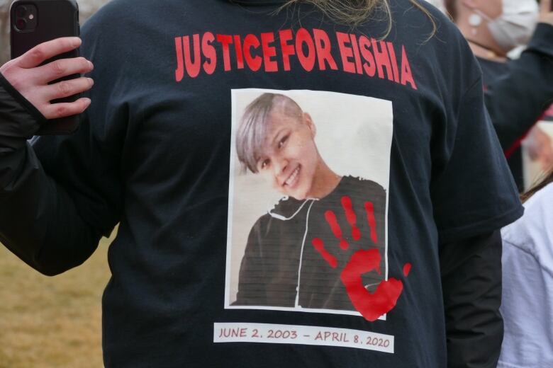 A person wears a black t-shirt with a picture of Eishia Hudson.