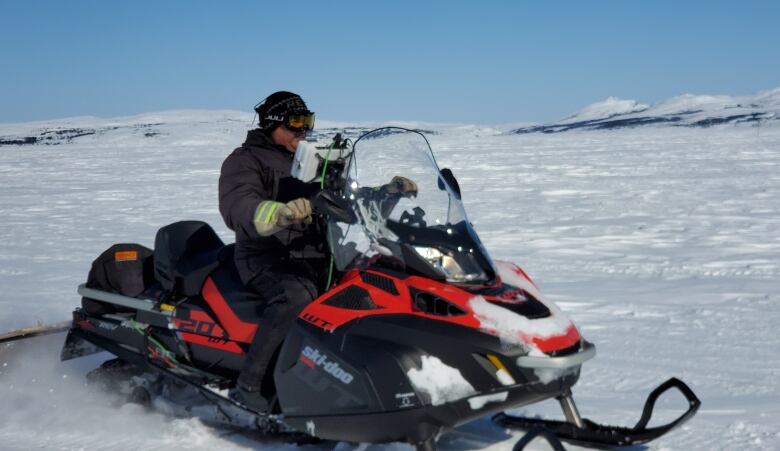 Rex Holwell sits on a snowmobile