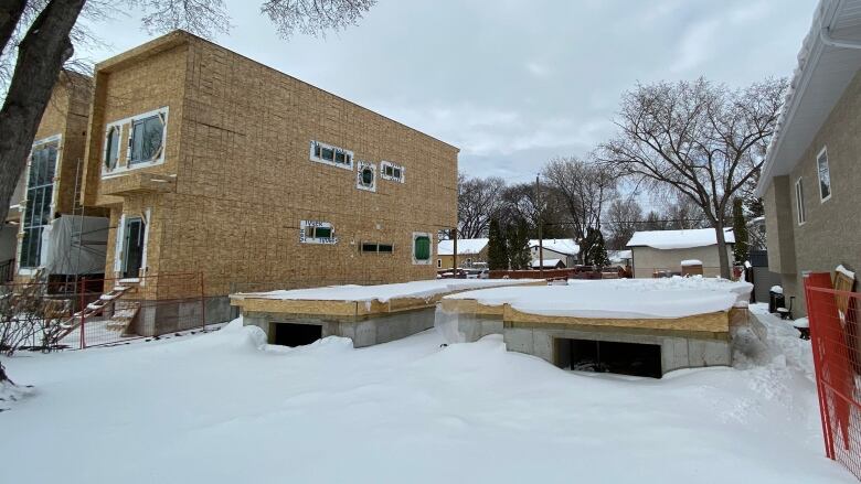 A photo shows a multi-unit building under construction in winter.