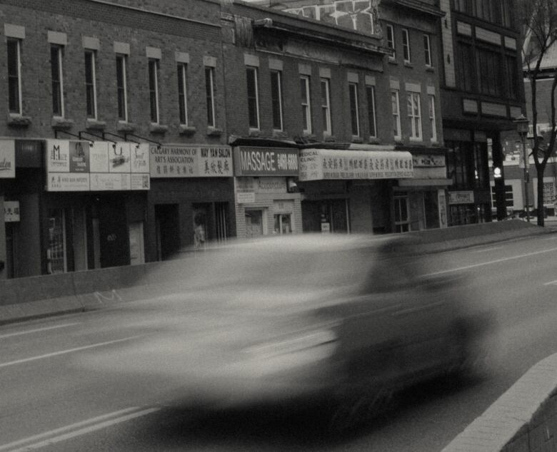 a blurry car drives down a street in Calgary's Chinatown