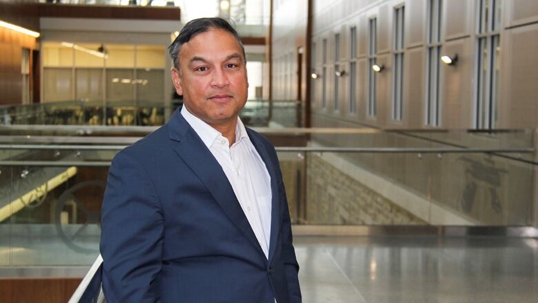 A man in a suit poses in a university building.