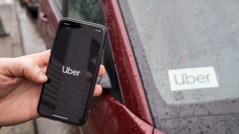 The Uber app is seen on an iPhone near a driver's vehicle after the company launched service, in Vancouver, Friday, Jan. 24, 2020. Uber Technologies Inc. drivers, couriers and passengers in Canada will be required to wear a mask starting Monday.