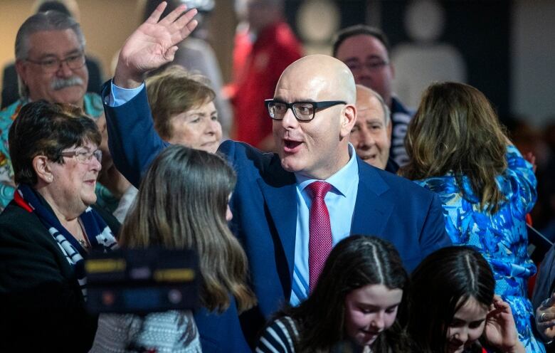 Steven Del Duca waves from the middle of a crowd.   