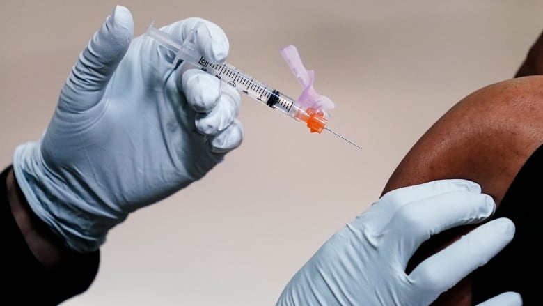 A member of the Philadelphia Fire Department administers a COVID-19 vaccine to a person at a vaccination site setup at a Salvation Army location in Philadelphia on March 26, 2021.