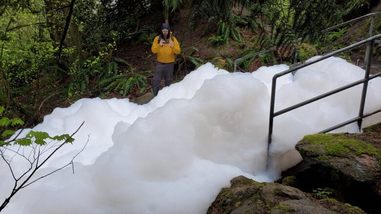 A man looks at piles of foam in a forest environment.