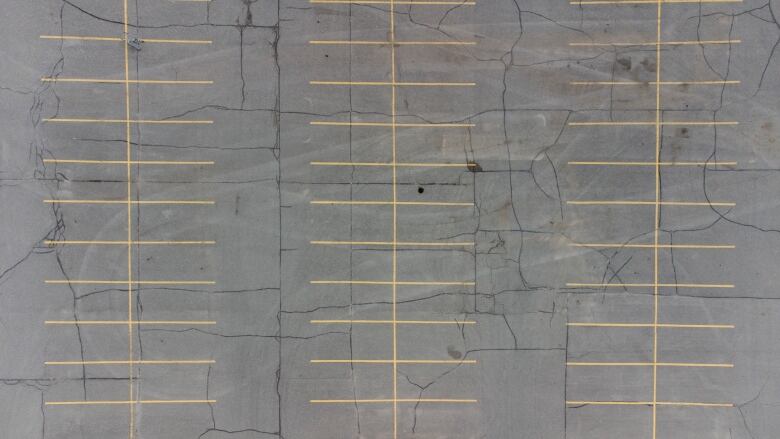 An aerial view of an empty concrete parking lot with yellow lines. 