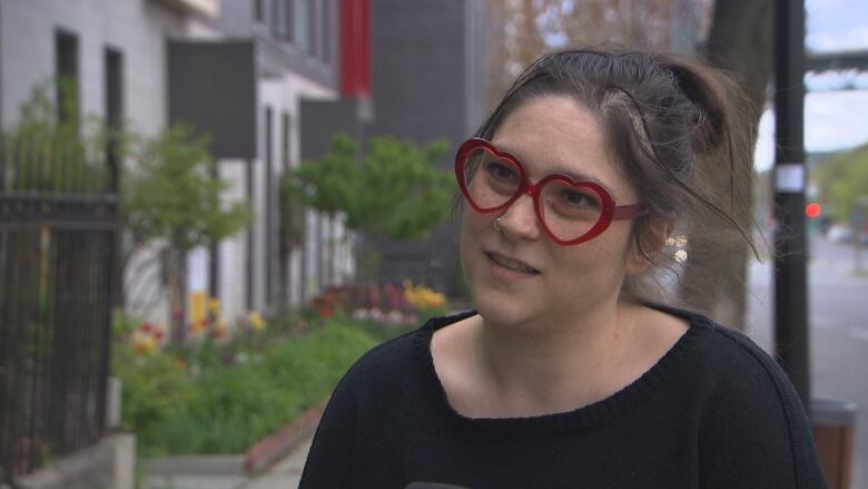 A woman wearing glasses speaks to an off-camera reporter. 