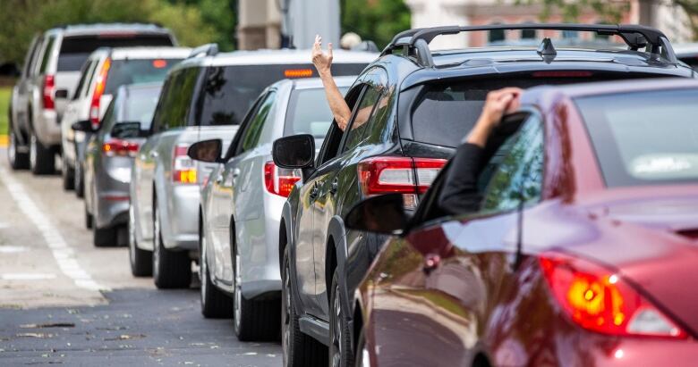 A series of cars wait in line at a gas station.