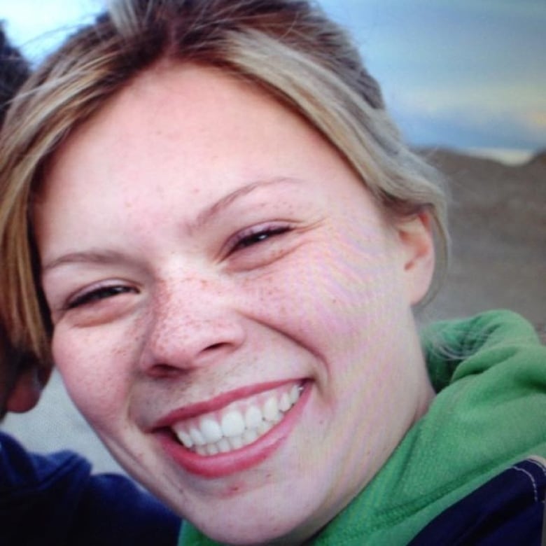 A young woman poses with a huge, happy smile on her face. 