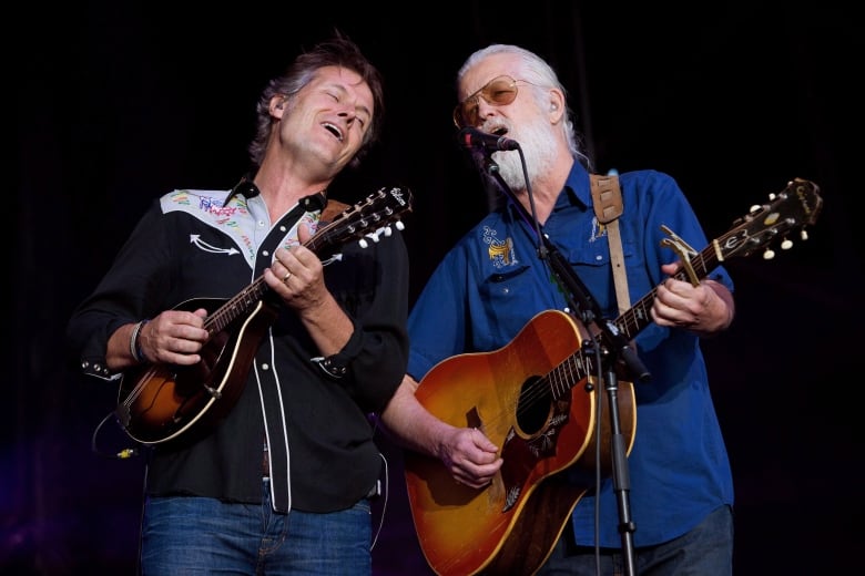 Two men play guitars and sing