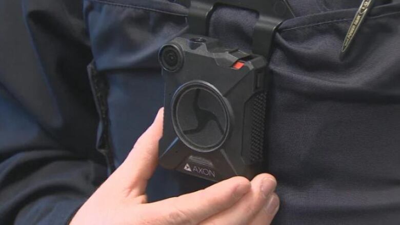 An officer holds a small camera.