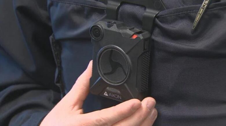 An officer holds a small camera.