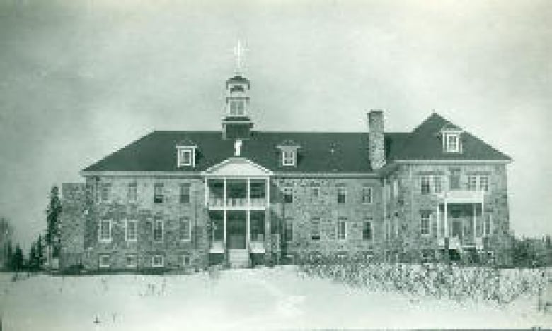 A black and white photo shows a large brick building.