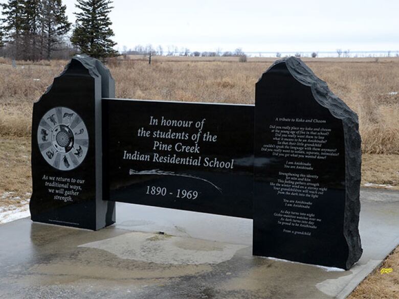 A black stone memorial plaque stands in a field. In the centre, it reads, 