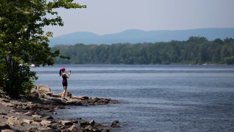 A woman stands on the shore of the Ottawa River.