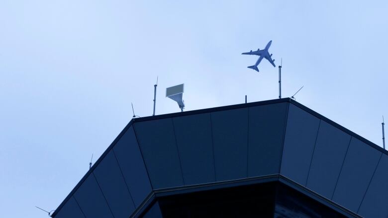 A plane flies over an air traffic control tower 