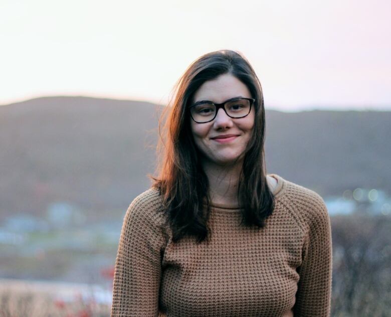 A young woman with black hair and dark rimmed glasses.