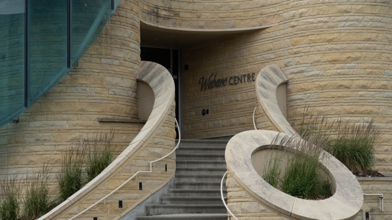 The exterior of a beige building, with a staircase and some plants.