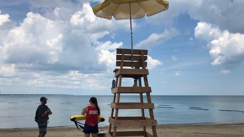 A lifeguard talks to a man on a beach next to a lifeguard station