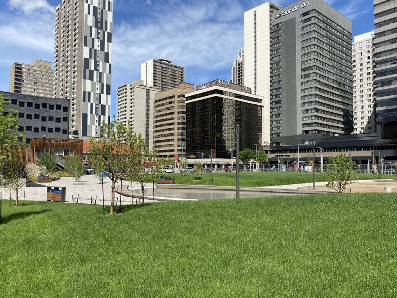 A green park overlooking skyscrapers in downtown Calgary.