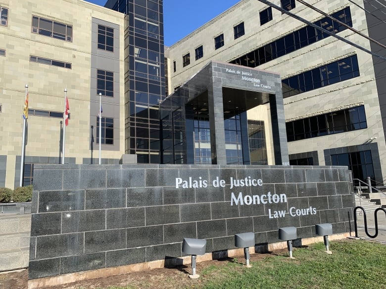 A large grey building with a bilingual sign in front indicating it's the Moncton Law Courts.