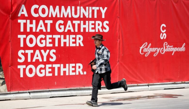 A man walks past a red sign with white writing.