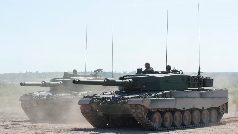 Two tanks carrying soldiers are shown side by side.