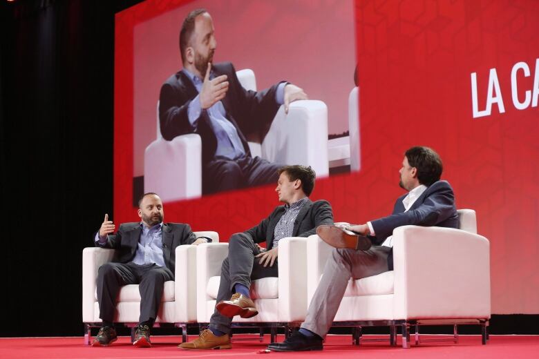 Three men sit and talk during a convention.