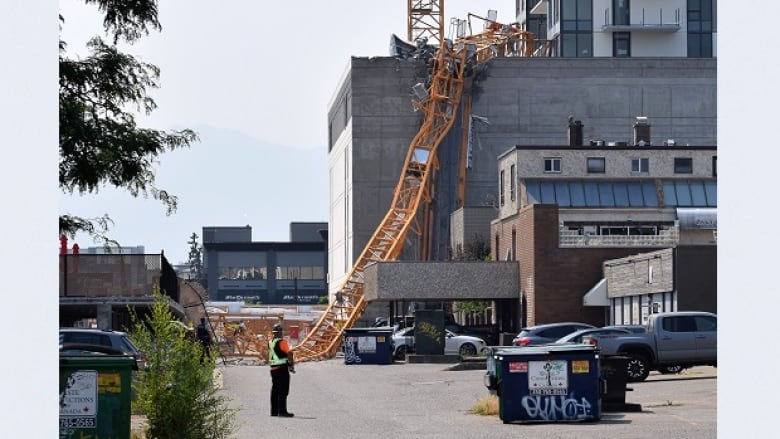 A collapsed yellow crane sits on top of a crushed office building.