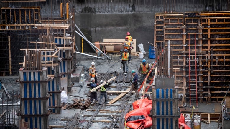 Workers move lumber at a condo construction site in Toronto on March 20, 2020.