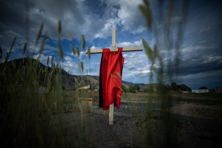 A cross with an orange tshirt on it.