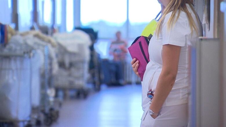 A nurse stands in a hallway.