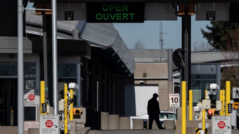 A Canada Border Services Agency officer is silhouetted at the Douglas-Peace Arch border crossing, in Surrey, B.C., on Monday, March 16, 2020. Prime Minister Justin Trudeau says Canada is closing its borders to most people who are not citizens or permanent residents to slow the spread of COVID-19. 