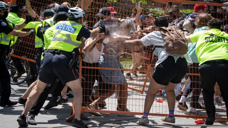 Several police officers and security staff struggle with civilians.