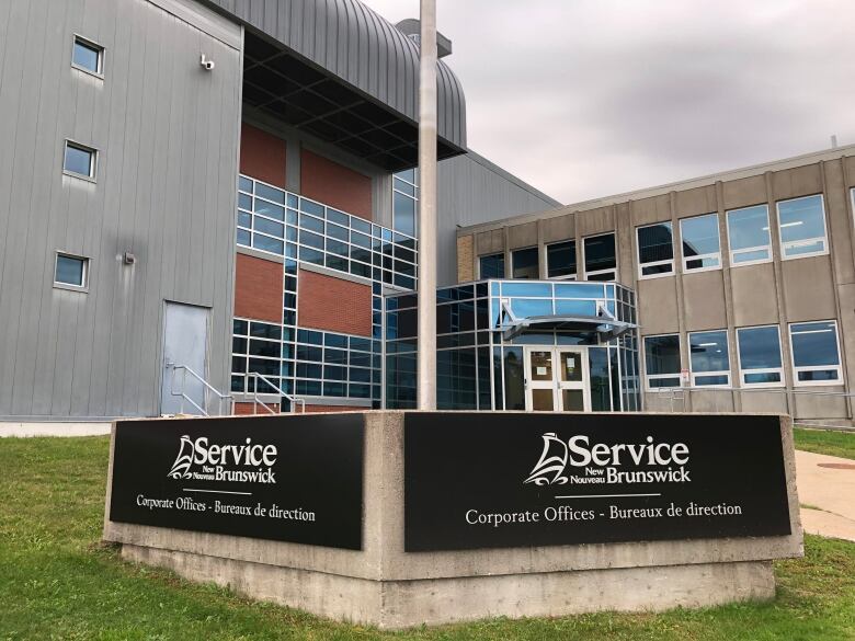 A building with lots of windows with a sign on the lawn in front of it that says 