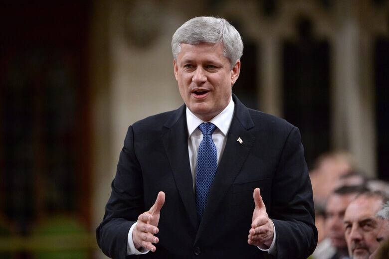 A man in a blue tie and dark suit stands and speaks in the House of Commons.