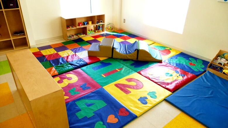 Colourful mats on the floor next to a shelf with children's toys.