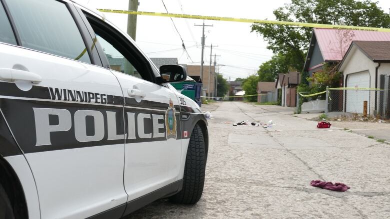 A police cruiser near a crime scene in a back lane.