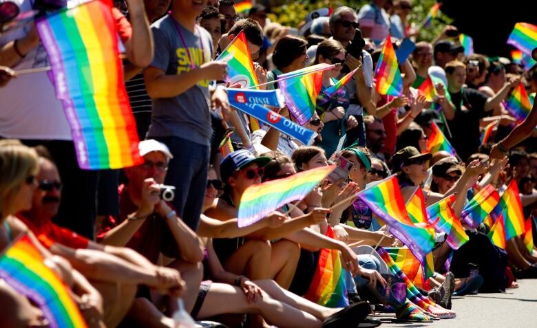 Spectators are shown waving Pride flags. 