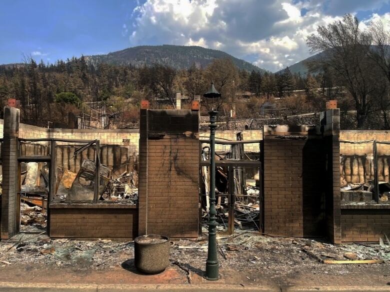 A brick structure in the foreground of burned property in Lytton B.C.