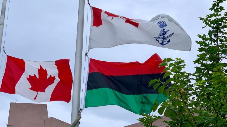 The Canadian flag, the pan African flag and the Canadian Navy Ensign are seen blowing in the wind