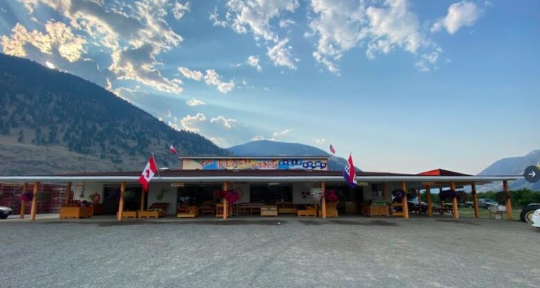 A fruit stand reading 'The Peach King Fruit Stand', with mountains behind it.