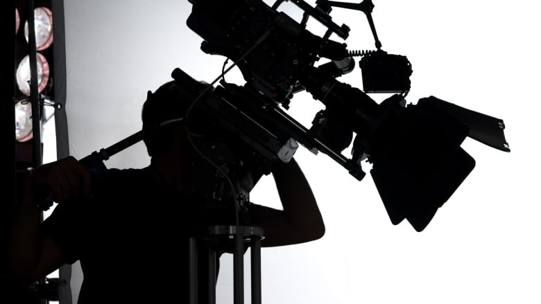 The silhouette of a person manning a large camera