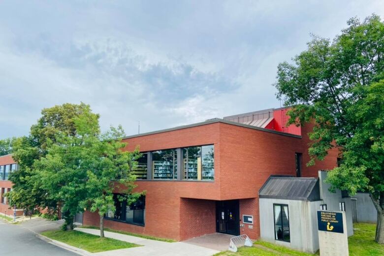 A low, red brick building with trees around it.