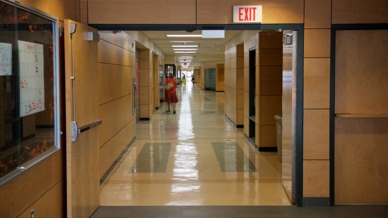 The hallway of a school with someone standing off in the distance.