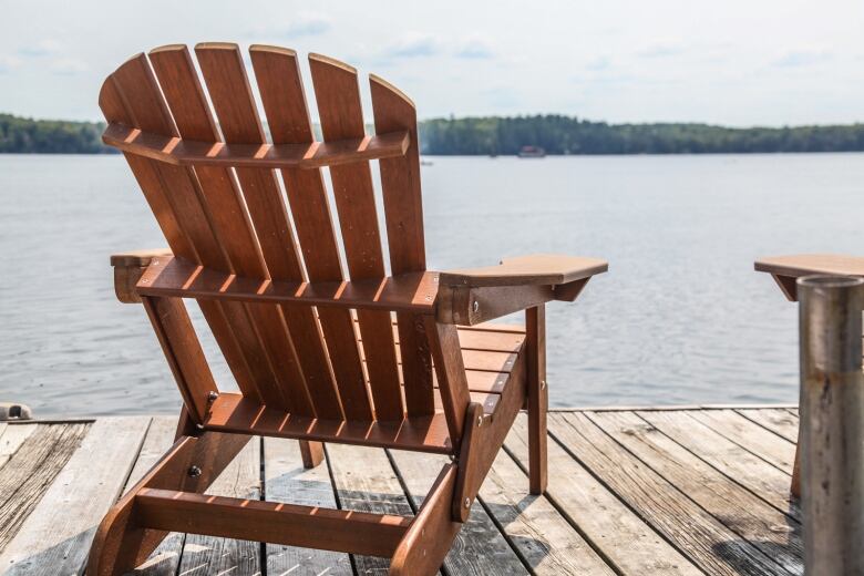 A Muskoka chair sits on a floating dock with water in the background.