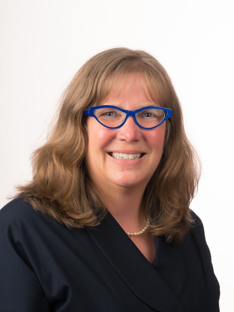 A smiling woman wearing blue glases.