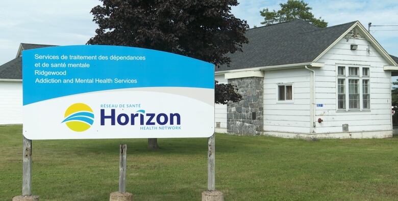 A blue and white sign stands in front of a low white building.